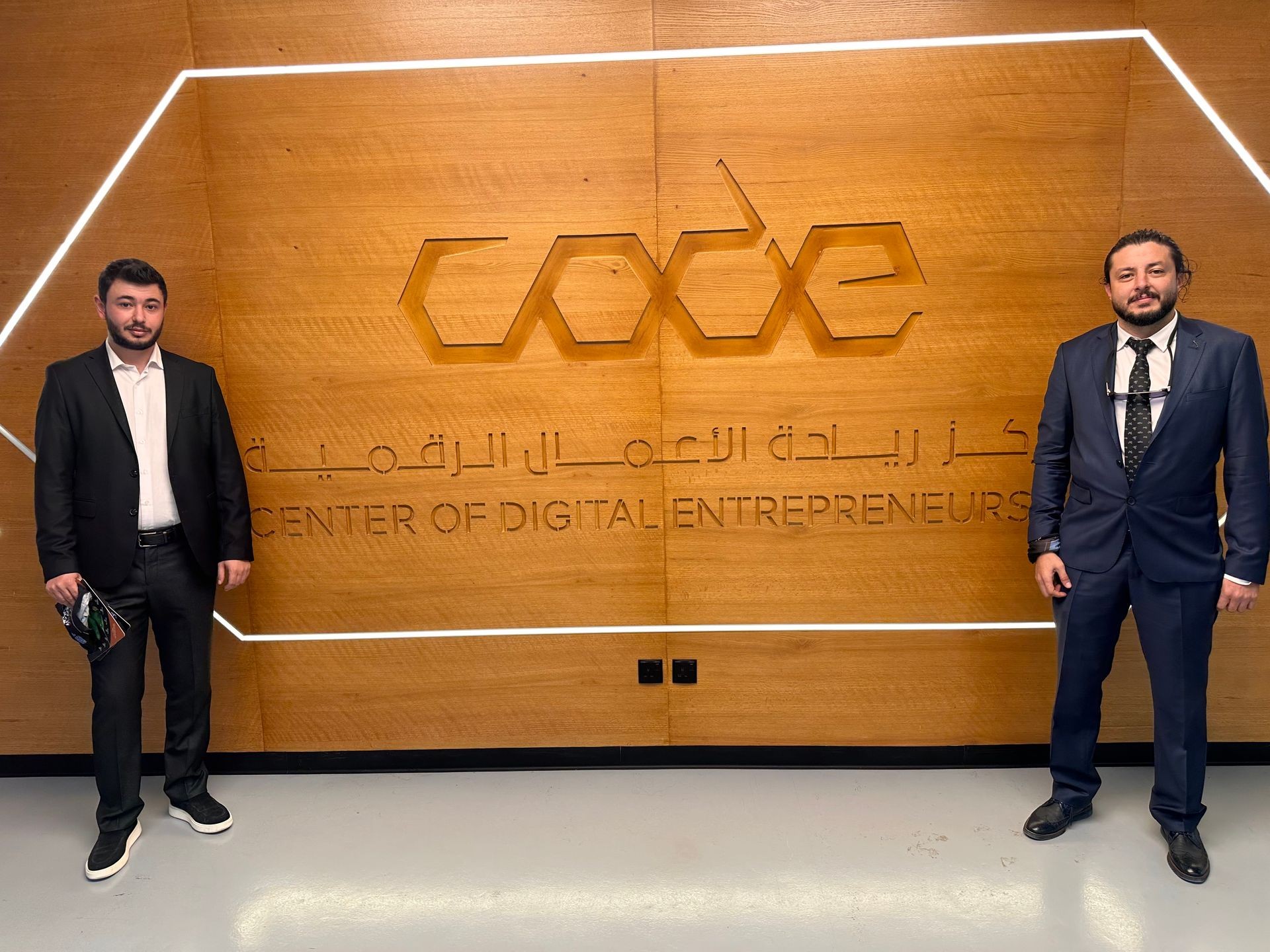 Two men in suits standing in front of the Center of Digital Entrepreneurs sign.