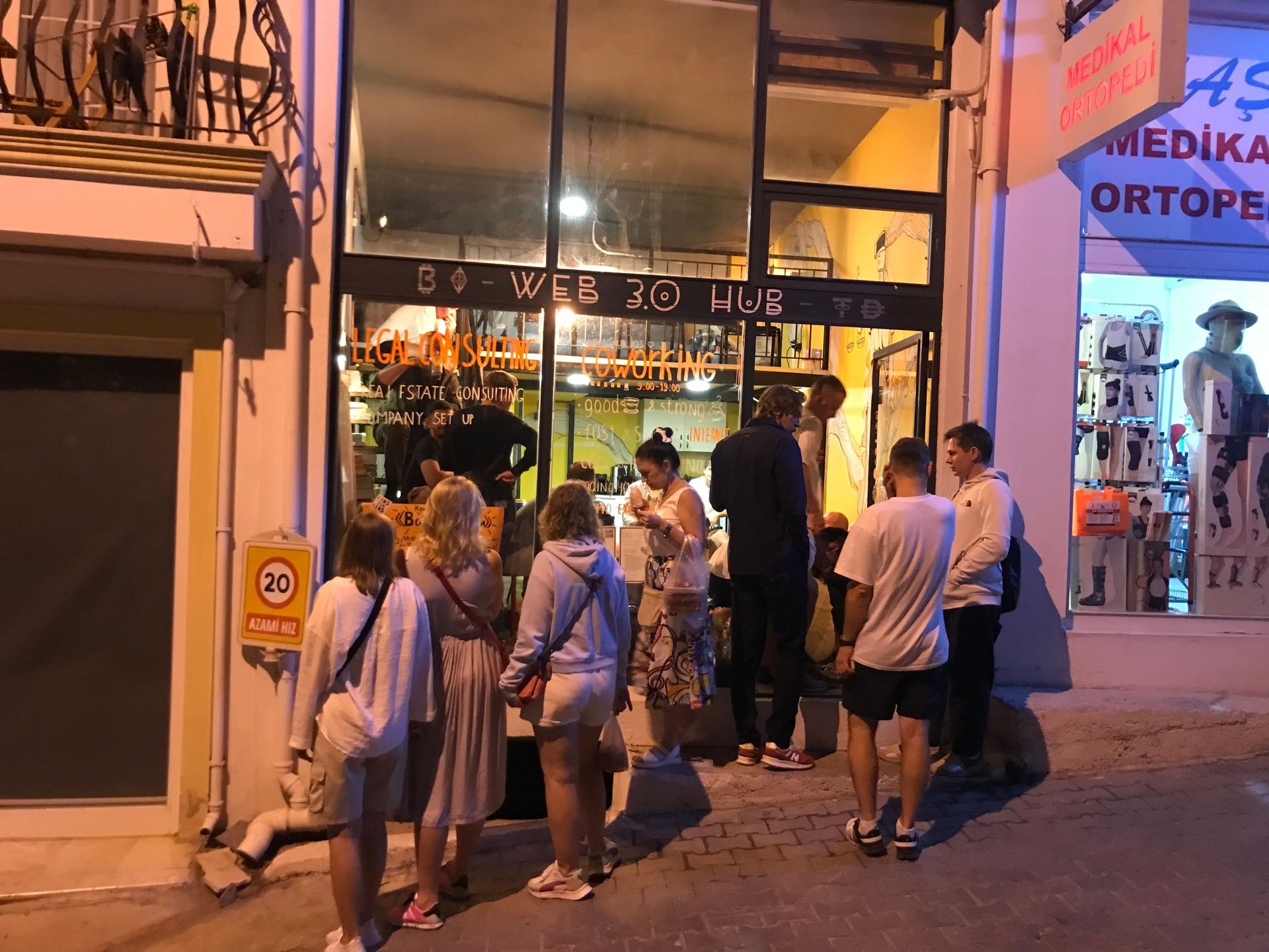 People standing outside a Web 3.0 hub at night with visible signage and storefronts.