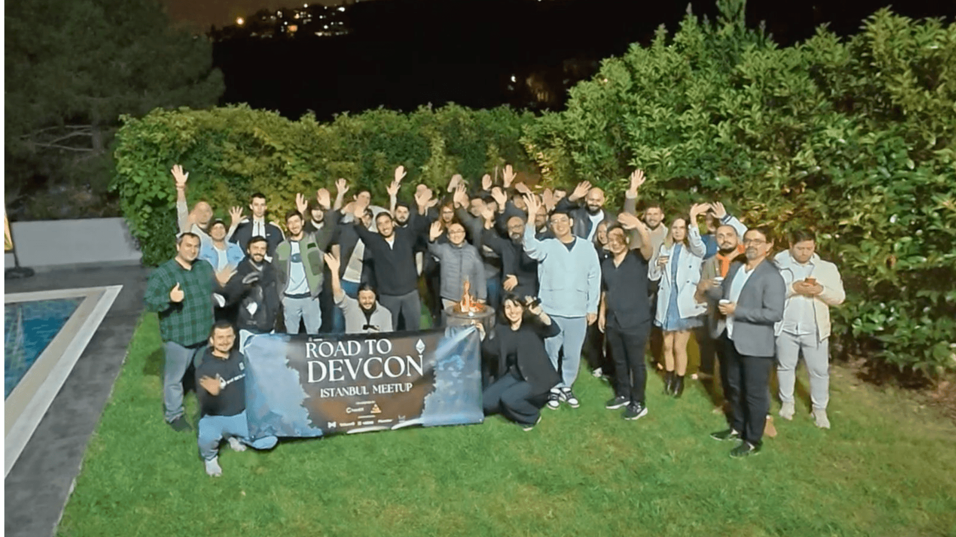 Group of people at an outdoor gathering holding a 'Road to Devcon Istanbul Meetup' banner.